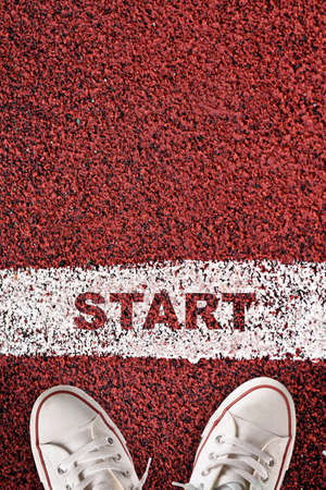 Top view of start word on starting line and white sneaker on red sport track. Business success concept and challenge ideaの写真素材