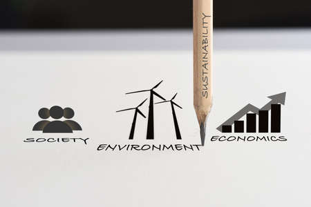 Drawing sustainable future concept and economic growth with environment idea. Environment society and economics written on white paper with pencilの写真素材