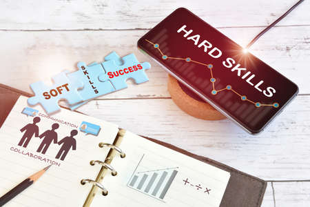 Hard skills business success and finance technology growth graph on smart phone on wireless charger with soft skills written on blue puzzle. Ability and talent concept with empathy collaboration ideaの写真素材