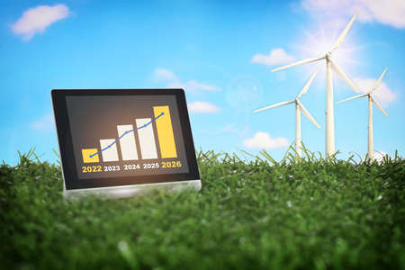 2022 to 2026 sustainable business strategy and financial growth graph stock trading on computer digital tablet with wind turbine on green grasses. Smart technology concept and responsibility ideaの写真素材