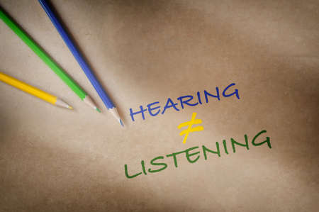 Colorful hearing not equal listening written on brown paper background with color pencil. Communication with understanding concept and soft skill ideaの写真素材