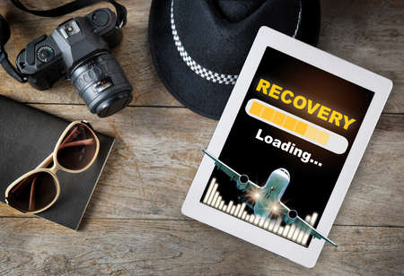 Airplane business travel concept and freedom idea. Recovery loading on computer digital tablet with airplane and growth graphの写真素材