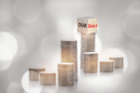 Our goals on cube on stack of coins on abstract background. Return on investment concept and business success ideaの写真素材