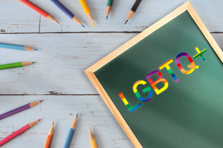LGBTQ+ written on chalkboard with colored pencil on wooden desk. Empathy concept and equality ideaの写真素材