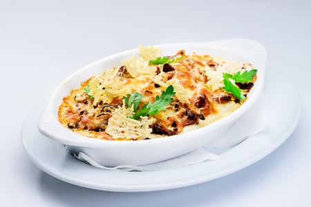 Tasting and appetizing traditional Italian lasagna dish with mushrooms  served with fresh dill in a white plate against light background. Autumn menu in an Italian restaurant.の写真素材