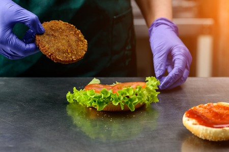 Unidentified chef preparing veggie burger with yummy vegetableの写真素材