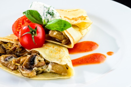 Homemade tasty pancakes blinis served with mushrooms and tomatの写真素材