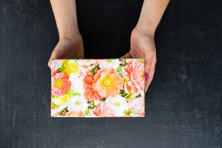 female hands holding a box in the square shape with a present onの写真素材