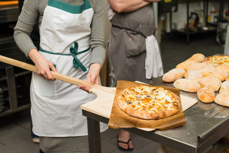 hot cooked Margarita Italian pizza with cheese, mushrooms and tomato sauce on wooden board. Cooking...