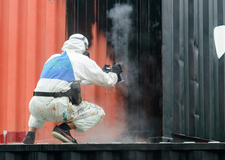 man painting with graffiti aerosol can, outdoors. Process of pai