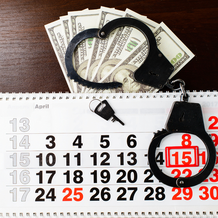 steel police handcuffs, dollars money and April 15 on calendar oの写真素材