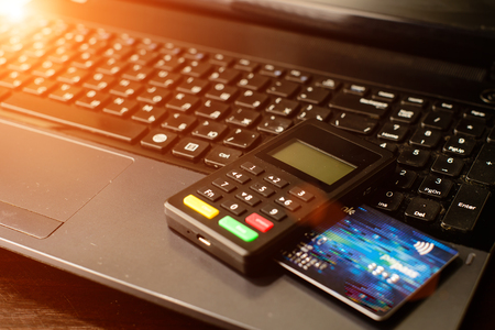 bank card and payment device lying on keyboard in rays of the suの写真素材