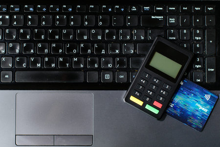 bank card and payment device lying on keyboard, top view. Concep