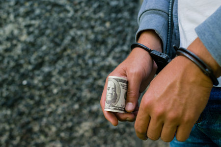arrested Hispanic man in handcuffs with dollar banknote. Arreste