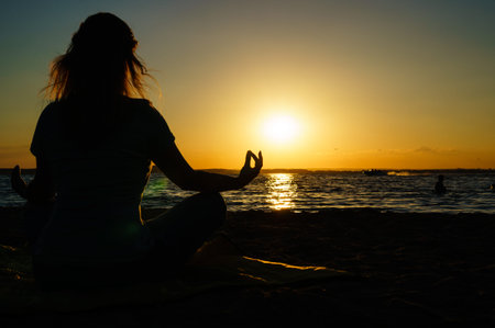 Woman practices yoga and meditates in the lotus position on the