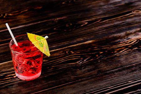 Top view of glass of red cocktail with ice cubes and straw umbreの写真素材