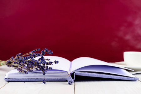 Purple notebook, cup of coffee and flowers on light wooden backgの写真素材