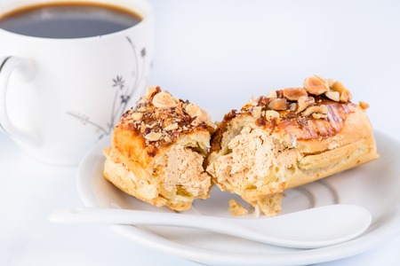 Appetizing sweet dessert. Cupcake with cream and nuts and cup of coffee on light backgroundの写真素材