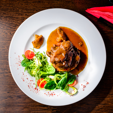 Meat dish. Appetizing beef cheeks in sauce with tomatoes and basilの写真素材