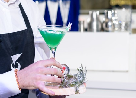 Unidentified barman holding a martini glass with green alcoholicの写真素材