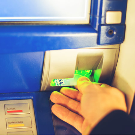 Hand inserting ATM card into bank machine to withdraw money
