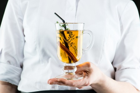 The unidentified waiter brings a hot Amaro cocktail with apple juice and cinnamonの写真素材