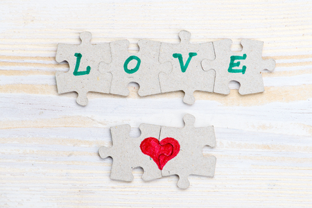 Word Love and heart made of pieces of jigsaw puzzle on light wooの写真素材