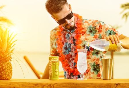 Handsome bartender standing near the bar counter, preparing cockの写真素材