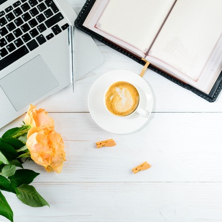 Have A Nice Day concept. Cup of coffee with fresh beautiful flowers and laptop on light table. Top view, flat layの写真素材