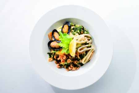 Fresh seafood salad with prepapred clams, shrimp and lemon in a white plate isolated on white backgroundの写真素材