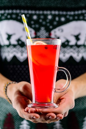Man holding hot cranberry tea with lemon and cinnamon in a glassの写真素材