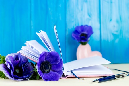 Pink notebook, pen and blue Anemone flowers. Concept of planning day and future goalsの写真素材