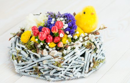 happy easter, yellow chick in the nest with fresh flowersの写真素材