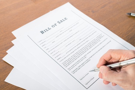 mans hand with pen sign the bill of saleの写真素材
