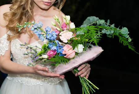 wedding bouquet in hands of the bride close-up on a dark background. Trendy and modern wedding flowersの写真素材