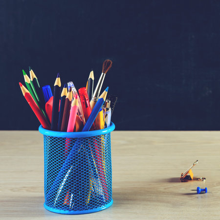 Stand for pen with pencils and colorful paper clips on wooden ta