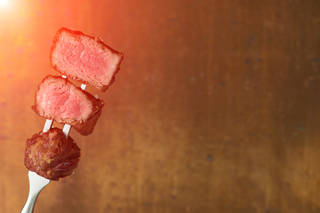 sliced steaks impaled on meat forkの写真素材