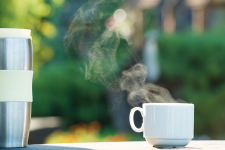 Cup of coffee or tea with steam and thermos on natural abstractの写真素材
