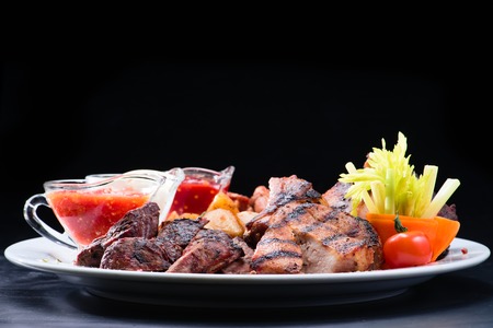 appetizing cooked beef steaks with tomato sauce and herbs on a white plate. Dark backgroundの写真素材