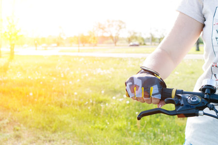 close-up rider s hand in gloves on a mountain bike handlebars in rays of the sun. Extreme sport conceptの写真素材