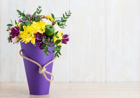 flowers in a cone box on a white wooden backgroundの写真素材