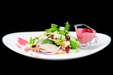 classic Italian food. Salad with chicken in a raspberry sauce on a white plate, dark backgroundの写真素材