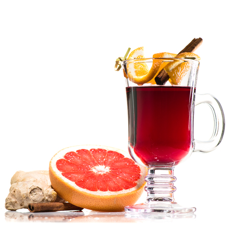 hot red mulled wine in glass with handle with cinnamon sticks and orange isolated on white background. Slice of orange and ginger near the glassの写真素材