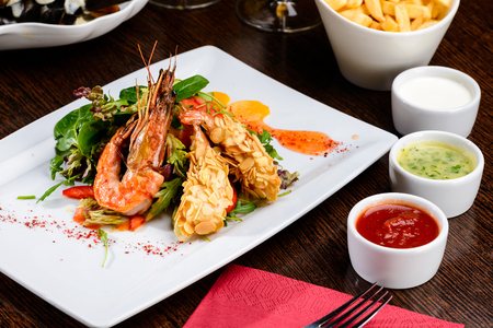 Delicious prepared shrimp with tomatoes, sauce and basil leaves at a restaurantの写真素材