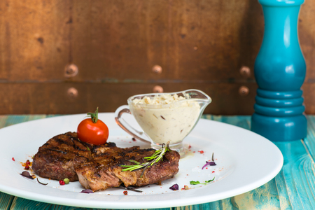 delicious steak from marble beef medium rare with tomatoes and herbs on a white plate, on a  wooden table. Brown background with copy space for textの写真素材