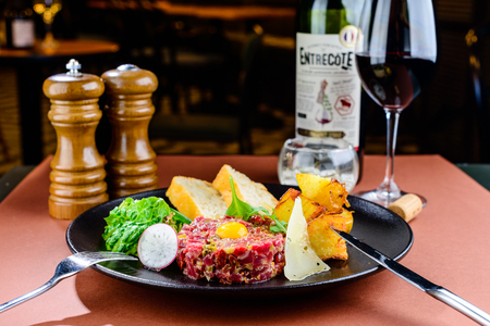 Raw tasty beef tartare with egg yolk and toasts on the plate in a cafeの写真素材