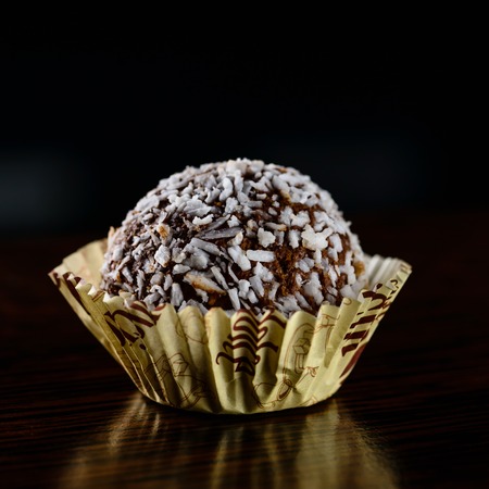 Chocolate coconut truffle with coconut flakes on dark background, close-upの写真素材