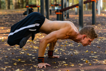 A handsome fitness man in a sportswear, guy doing gymnastics outdoorの写真素材