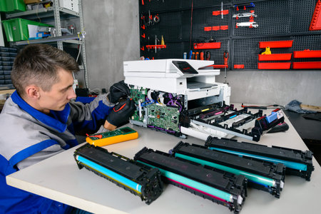 Man leaning over open photocopier during maintenance repairs using handheld tool