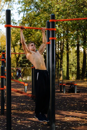 Muscular man doing pull-ups on horizontal barの写真素材
